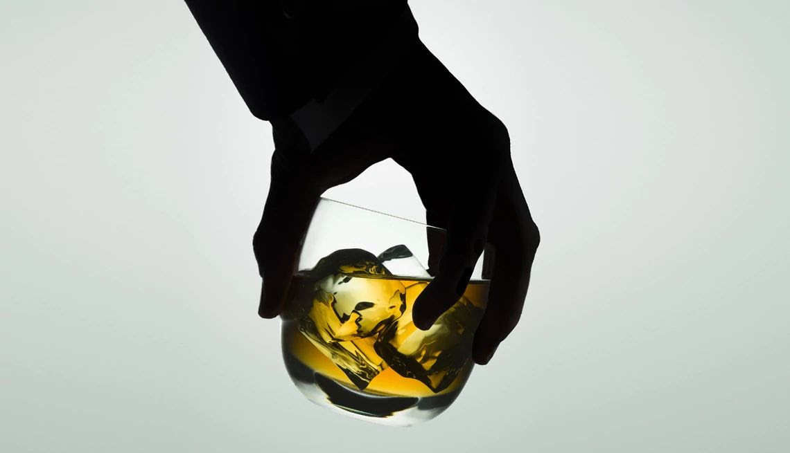 shadow of a hand holding a rocks glass