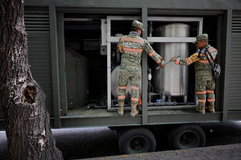 Soldiers place a water treatment plant in San Lorenzo Park in Mexico City, on April 11, 2024. - The inhabitants of a sector of Mexico City have been affected by the contamination of a water well with an oily substance, in the midst of an extreme drought that affects several parts of the Latin American country. In a second consecutive protest of dozens of people, the inhabitants of the central Benito Juarez mayor's office denounced that the water that comes out of the taps of their homes has "a smell of gasoline" and a "strange taste," which they told local media has caused some skin and eye damage. (Photo by ALFREDO ESTRELLA / AFP)