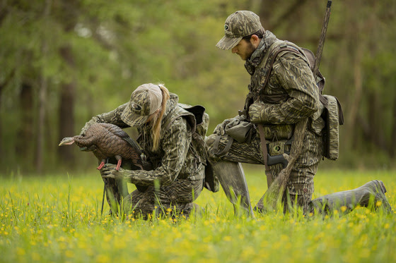 Two turkey hunters place a decoy into a field prior to starting their hunt. 