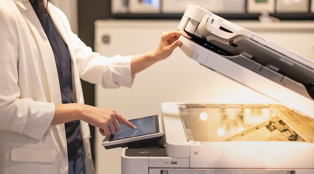 Female standing and hand pressing button on a copy machine in the office