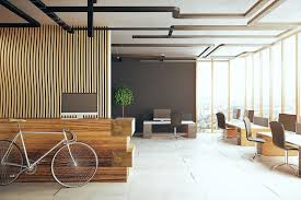 a stylish office lobby with a minimalist design aesthetic. It features wooden slats on the walls, a sleek dark ceiling with visible ductwork, full-length windows allowing natural light to flood the space, and comfortable seating areas. A vintage bicycle adds a unique decorative element to the room.