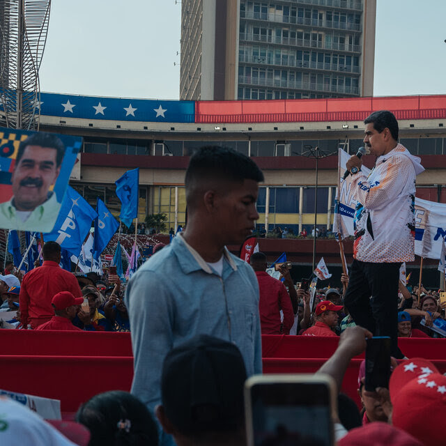 President Nicolás Maduro of Venezuela holds a microphone as he speaks to a crowd.