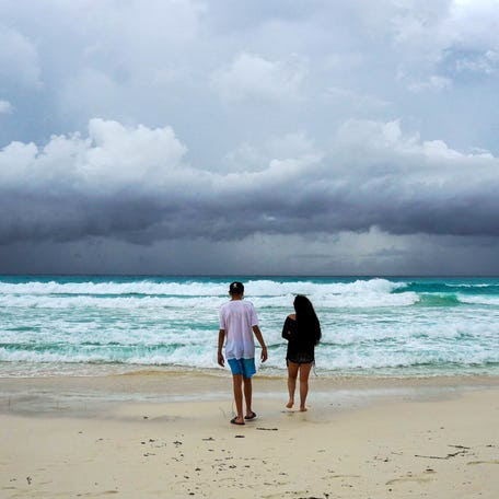 Storm clouds are pictured as a couple walks on the beach ahead of the arrival of Tropical Storm Helene in Cancun, Quintana Roo state, Mexico on September 24, 2024.