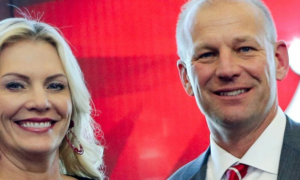 Alabama head coach Kalen DeBoer and his wife, Nicole, holding an Alabama jersey at his introductory press conference.