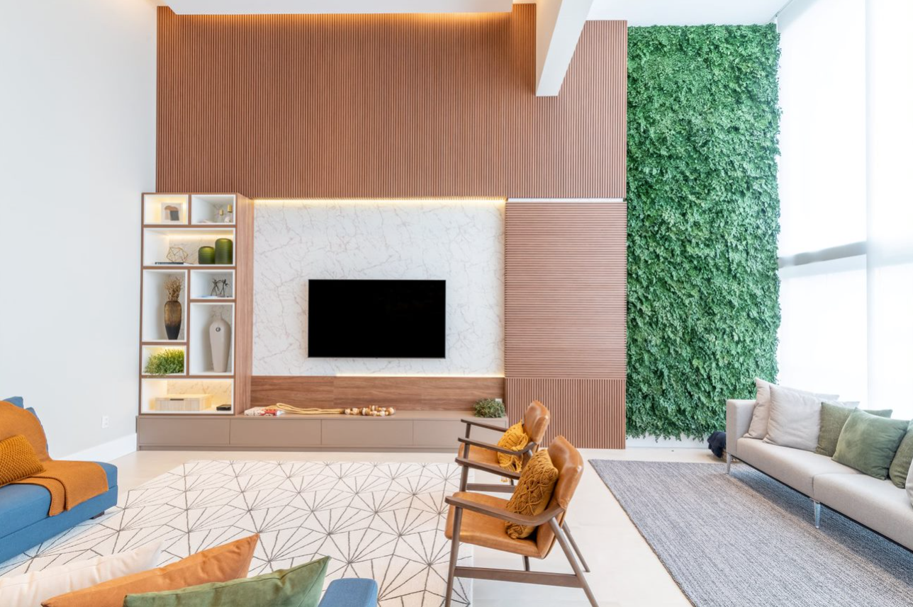 Desse lado do living, o revestimento ripado foi inserido em direções distintas para recobrir a parede e emoldurar o painel da TV em porcelanato. Ao lado, uma faixa de jardim vertical realizado com plantas preservadas | Projeto Marta Martins Arquitetura | Foto: Julia Herman