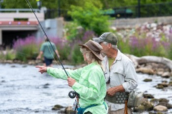 Two people wearing lightweight river-fishing gear survey the dark waters.