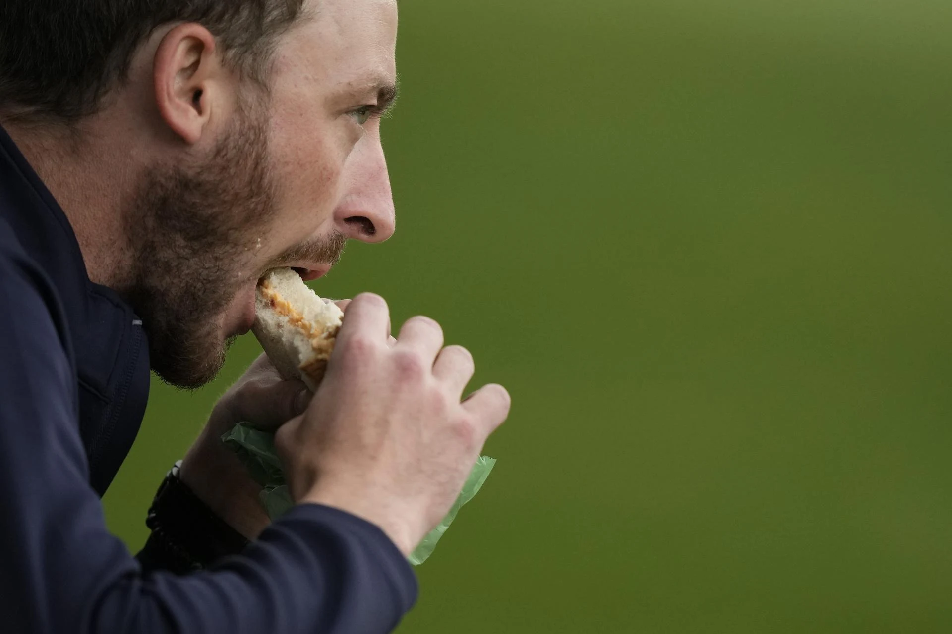 A patron eats a pimento cheese sandwich.