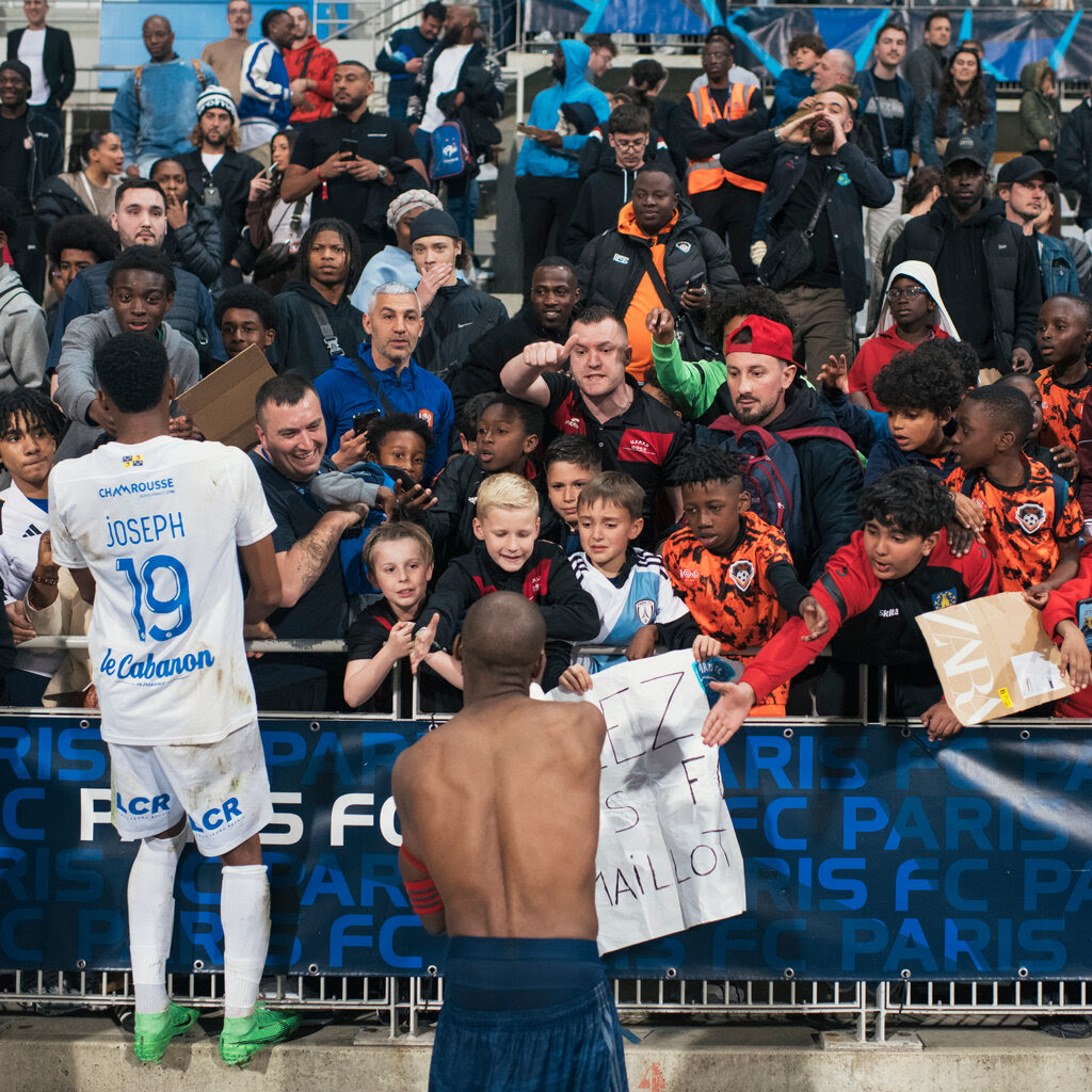 Fans lean over a railing while a player signs autographs.