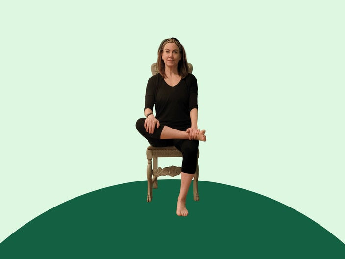 Woman doing chair yoga pigeon pose on green background.