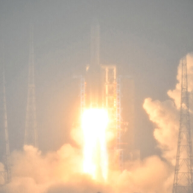 A rocket rises from its launchpad in a burst of flame and smoke.