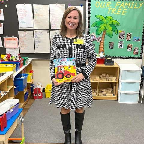 a photo of Chancellor Miller standing in a classroom and holding the book Dig, Dig, Digging