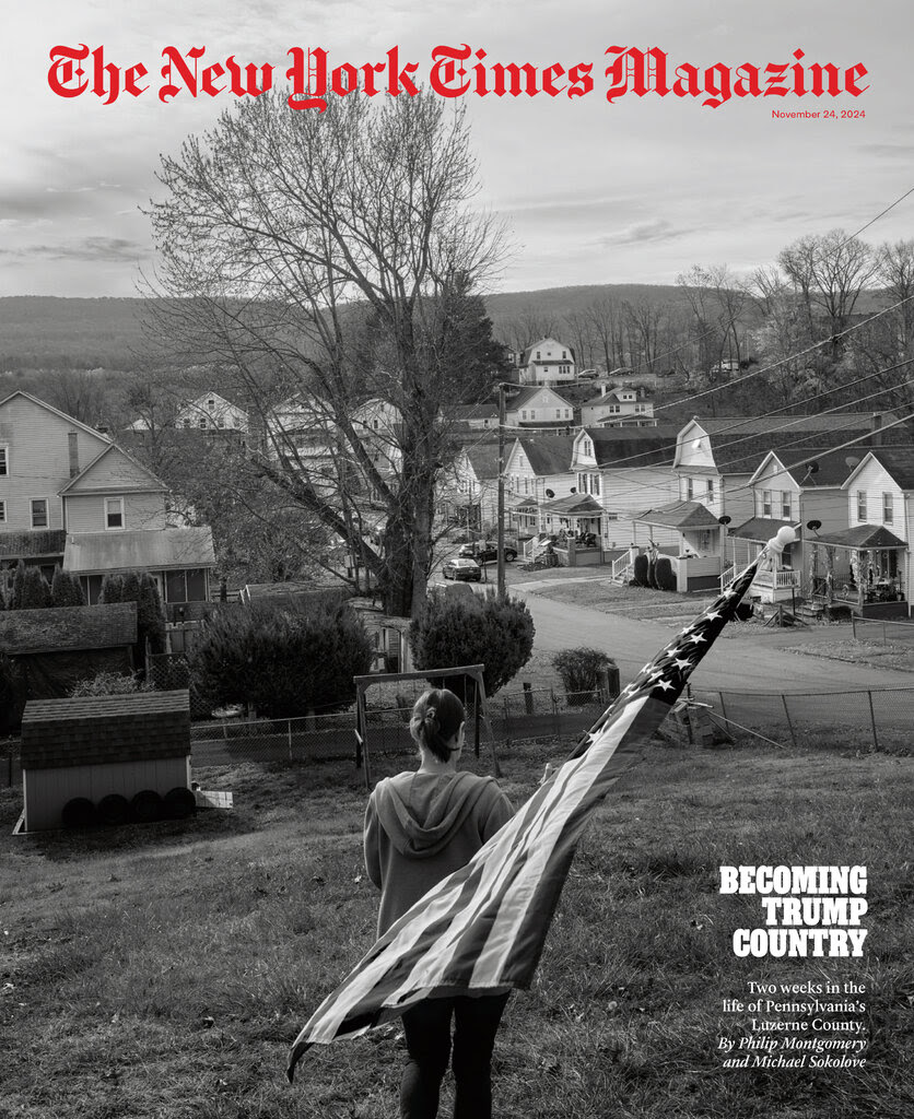 In a black-and-white photo, a person holds an American flag. In the background is a street lined with homes. The caption reads: "Becoming Trump Country."