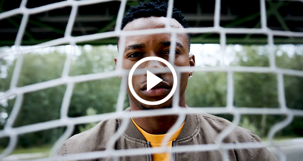 Man standing behind netting with a playbutton 