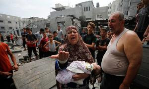 Familias palestinas frente a edificios dañados y destruidos por los bombardeos israelíes a Gaza.