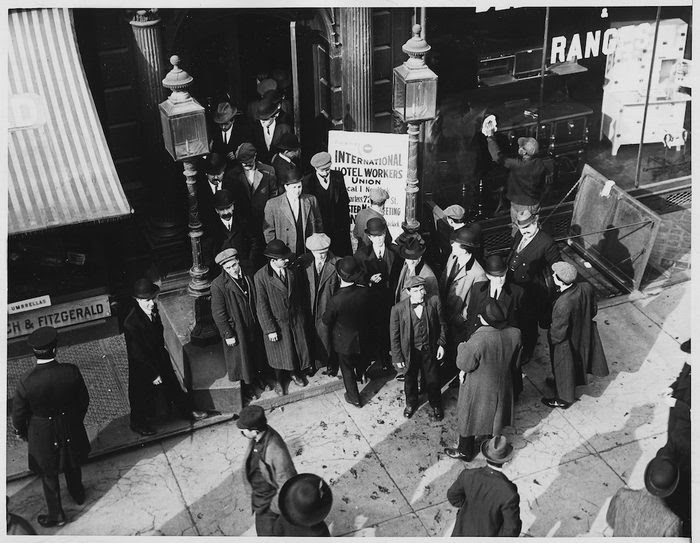 A black and white picture of a group of men standing in the street