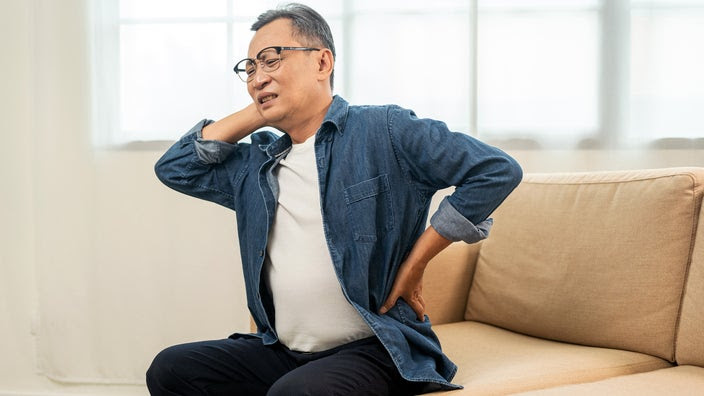 A man experiences pain while sitting on the couch.