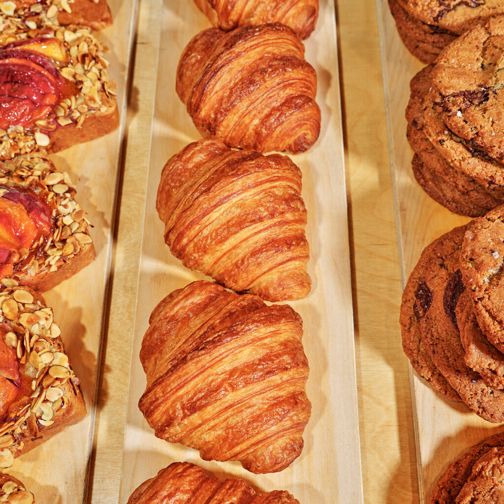 A display of croissants, cookies and other baked goods.