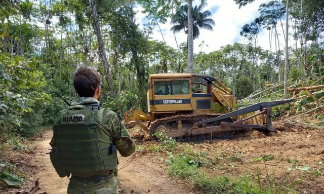 Servidor do Ibama em frente à maquinário apreendido na Amazônia durante operação