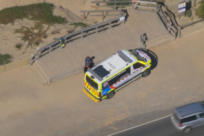 An ambulance parked in front of a beach.