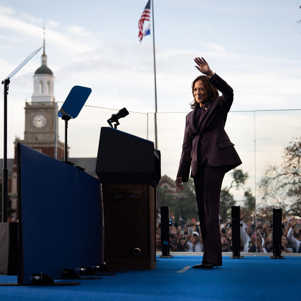 Kamala Harris waves to the crowd while standing near a lectern.