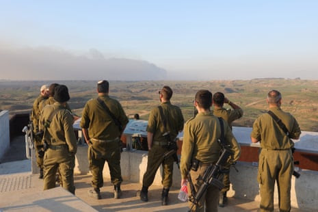 Israeli soldiers watch as smoke rises from Gaza at the border in southern Israel