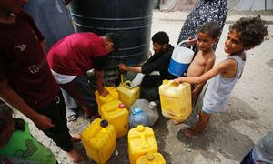 Unos niños recogen agua en la Franja de Gaza.