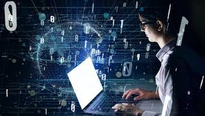 A woman sits at a laptop surrounded by floating 1s and 0s. She appears focused, typing or interacting with the laptop screen while the binary digits hover around her. This imagery symbolizes her engagement with digital technology, suggesting activities such as coding, data analysis, or digital communication.