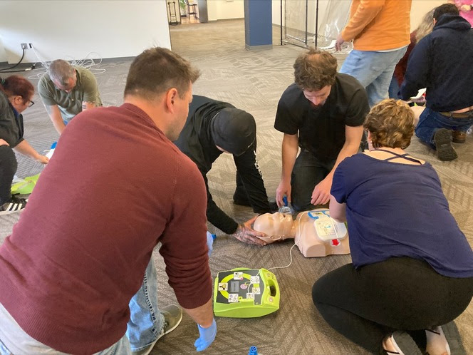 Several people using an automated external defibrillator on a human dummy during first aid training