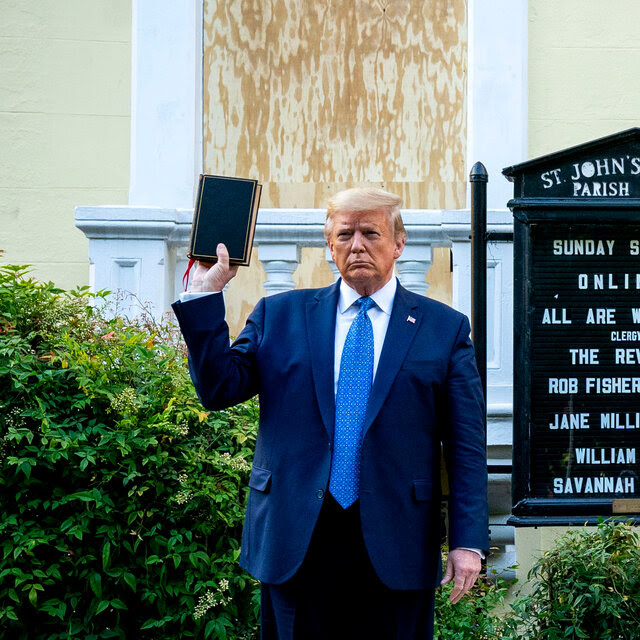 Former President Donald J. Trump holding a Bible in his right hand. A sign for St. John’s Church is behind him.