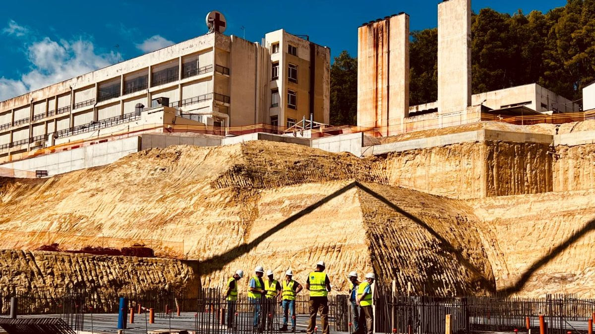 A team of construction workers stand, reviewing the excavations for the new SNF General Hospital of Sparta.