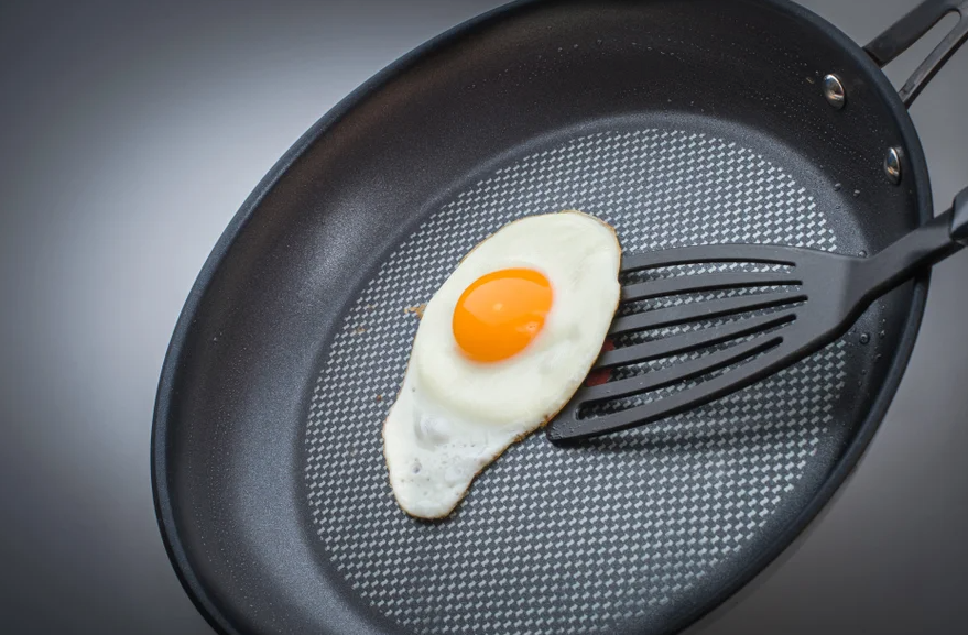 A black spatula flips a fried egg