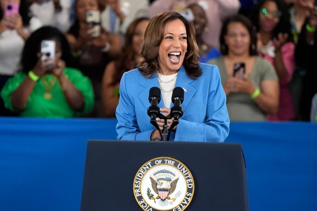 Vice President Kamala Harris speaking at a podium during a 2024 campaign event at Wake Tech Community College in Raleigh, N.C., with audience in background