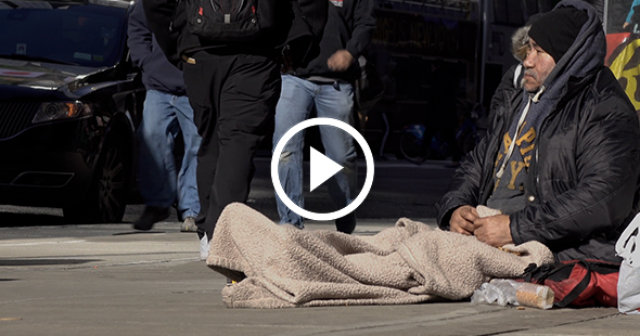 Man sitting on the ground with a blanket over his legs