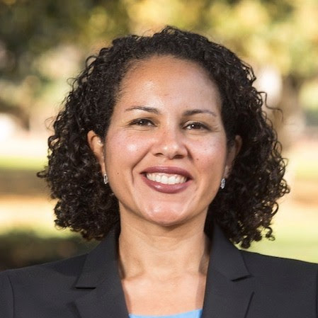 Smiling WOC with a red shirt, black jacket and red lipstick