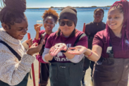 Lauren Johnson, far right, and other students pose on a beach holding up marine life specimens they found on an field visit.