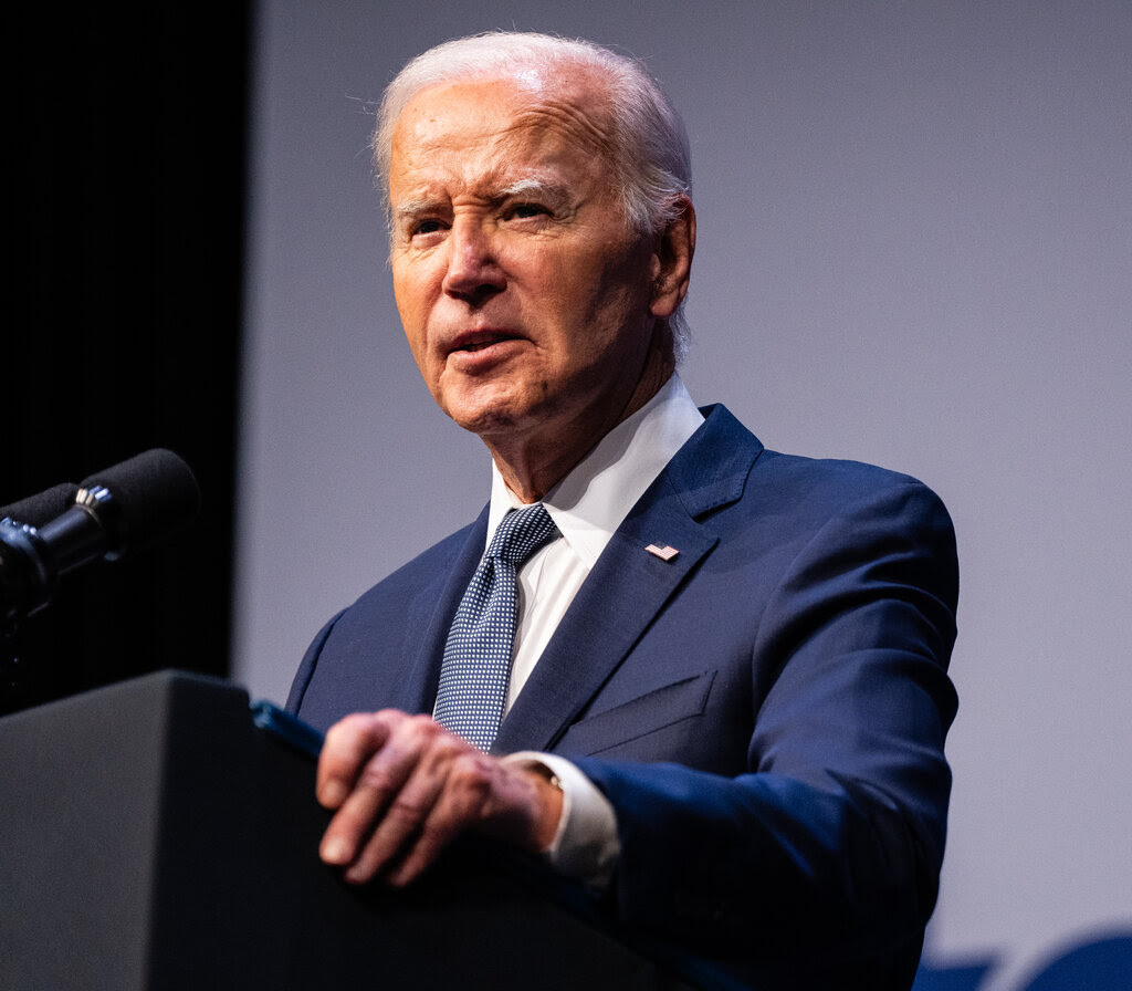 President Biden at a podium, wearing a dark suit and tie.