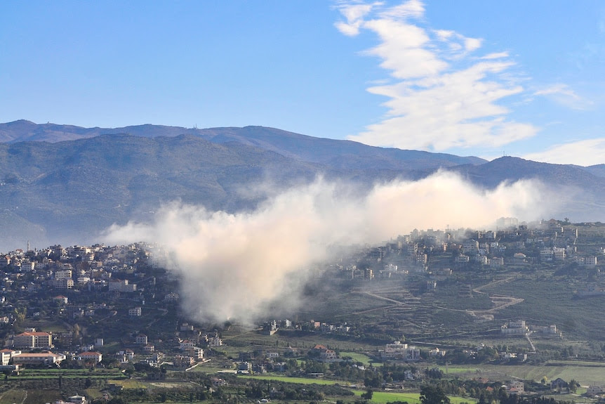 Smoke rises from village.