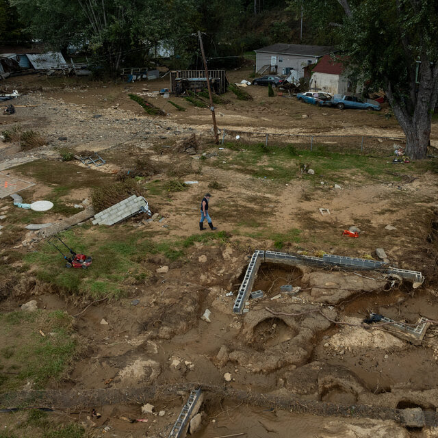 A view from above that shows a wrecked house with a person surveying the damages.