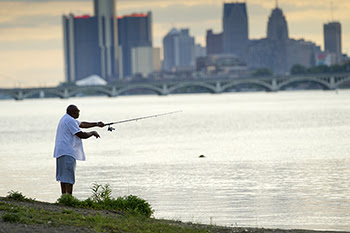 Angler fishing near Detroit skyline