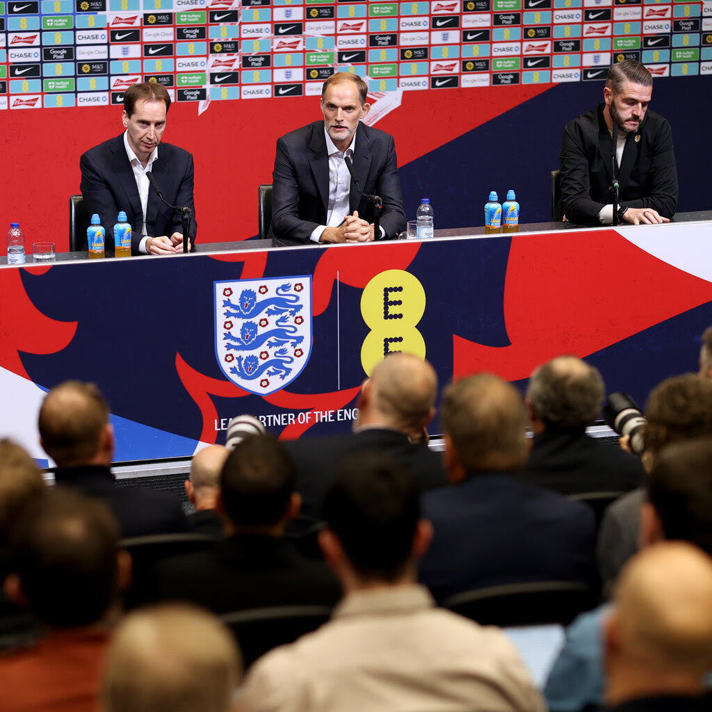 Thomas Tuchel, in a navy suit and white shirt, speaking to journalists at a news conference on Wednesday.