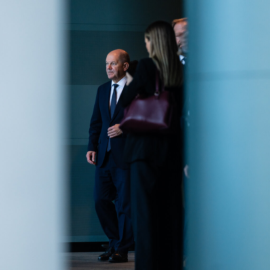 Olaf Scholz, the German chancellor, wearing a suit and standing between two pillars. 