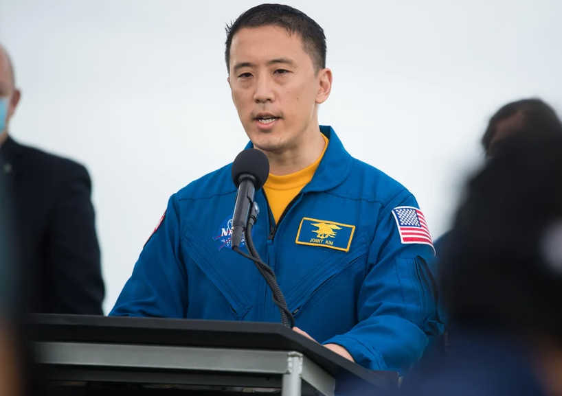 NASA astronaut Jonny Kim speaks into a microphone at a podium during a press conference