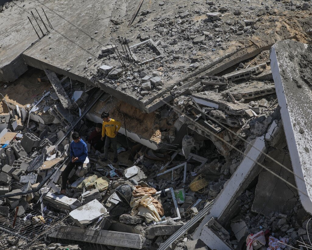 Two people survey the wreckage of a house.