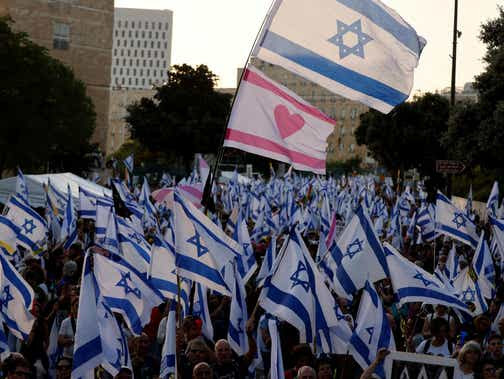 Israelis waving their national flag gather during an anti-government rally calling for early elections, outside the Knesset on Tuesday.