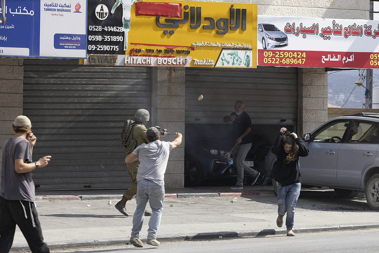 Israeli settlers, backed by Israeli soldiers, attack Palestinian residents, cars, and shops in the occupied West Bank town of Huwara, near Nablus, October 13, 2022. (Oren Ziv)