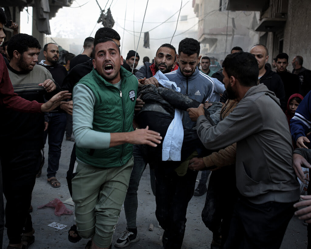 Palestinians run while carrying the body of a victim of airstrikes.
