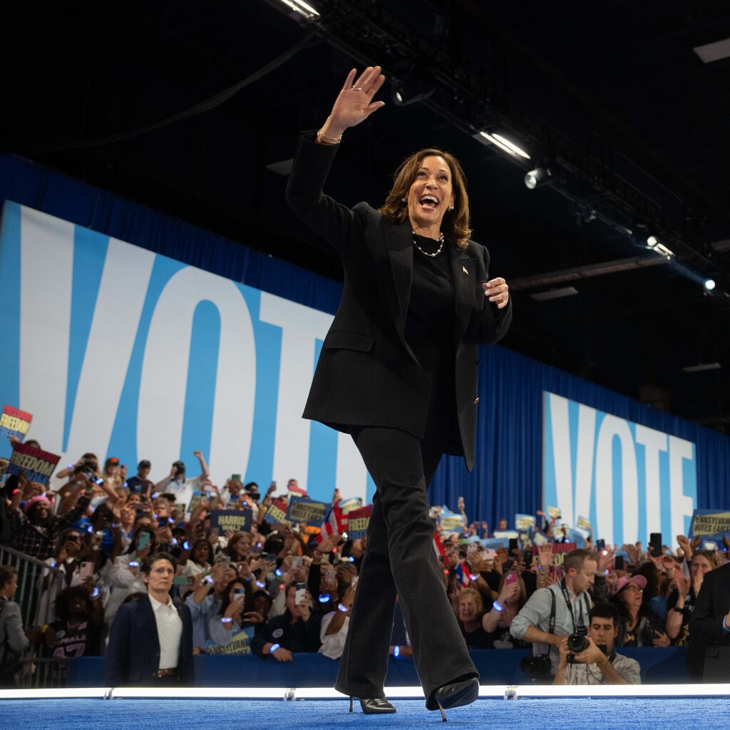 Kamala Harris in a black suit waving at a crowd. 