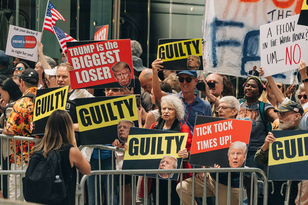 Protesters hold signs with slogans celebrating former President Donald Trump's guilty verdict.