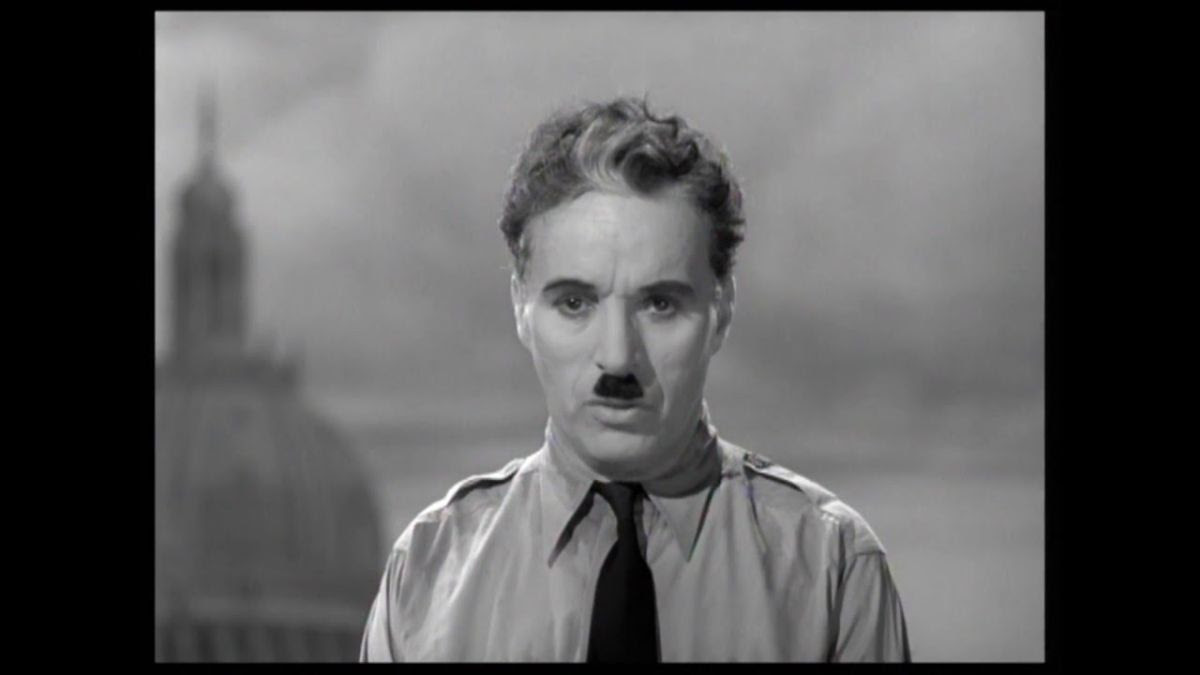 Charlie Chaplin, with a toothbrush moustache and wearing a shirt and tie, performs his famous speech in his film The Great Dictator.