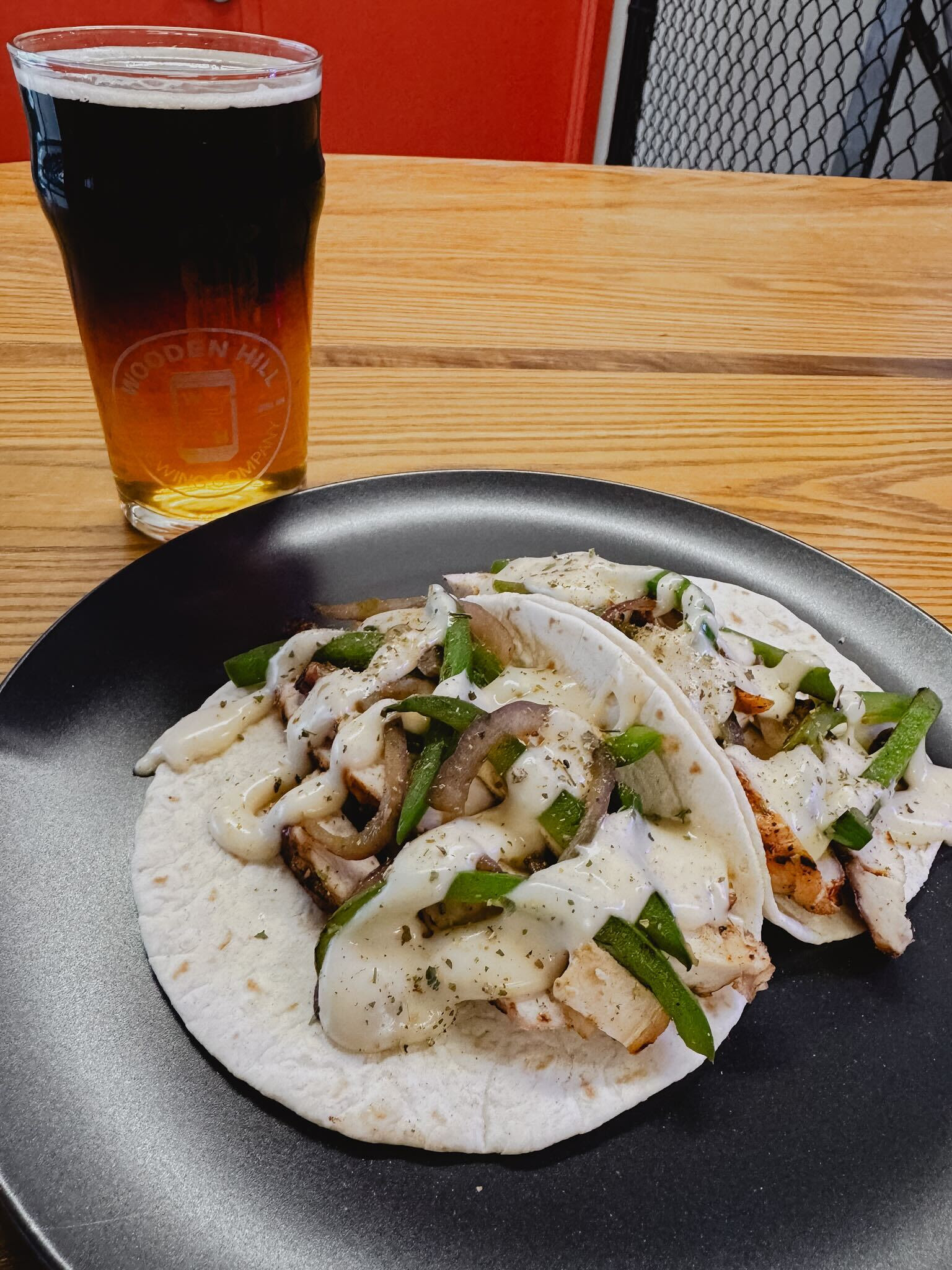 photo of 2 grilled chicken philly tacos next to a black and tan beer